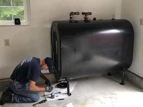 Technician installing oil tank fittings in Queens NY basement
